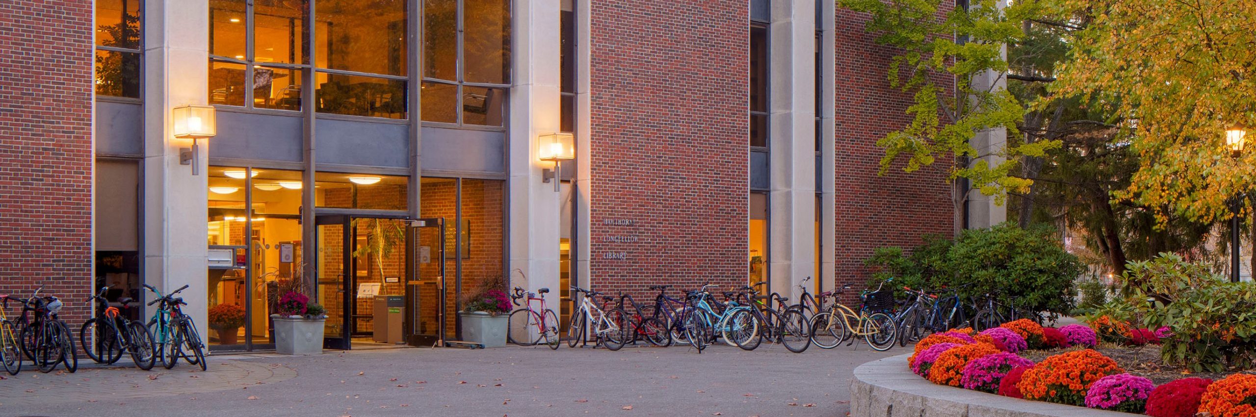 The entrance to Hawthorne-Longfellow Library with the doors open and lit by warm lamplight